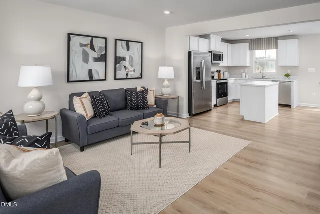 a living room with stainless steel appliances furniture and a kitchen view