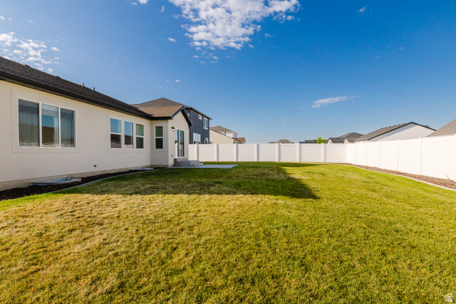 433 North 600 West Smithfield, UT 84335 - Photo 6 of 40 Expansive backyard featuring a large green lawn, full vinyl privacy fencing, and a concrete patio