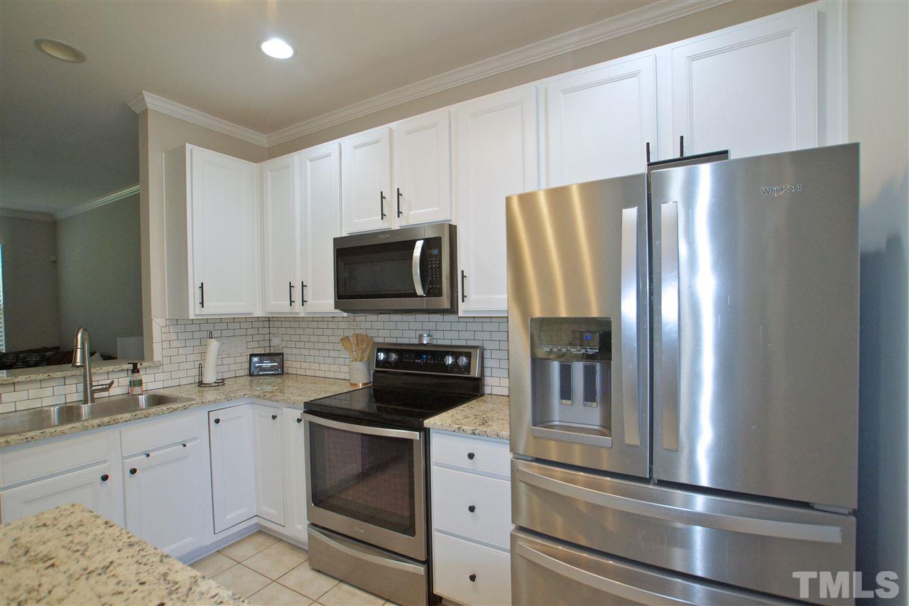 4807 Sir Duncan Way Raleigh, NC 27612 - Photo 11 of 29 a kitchen with a refrigerator stove and white cabinets