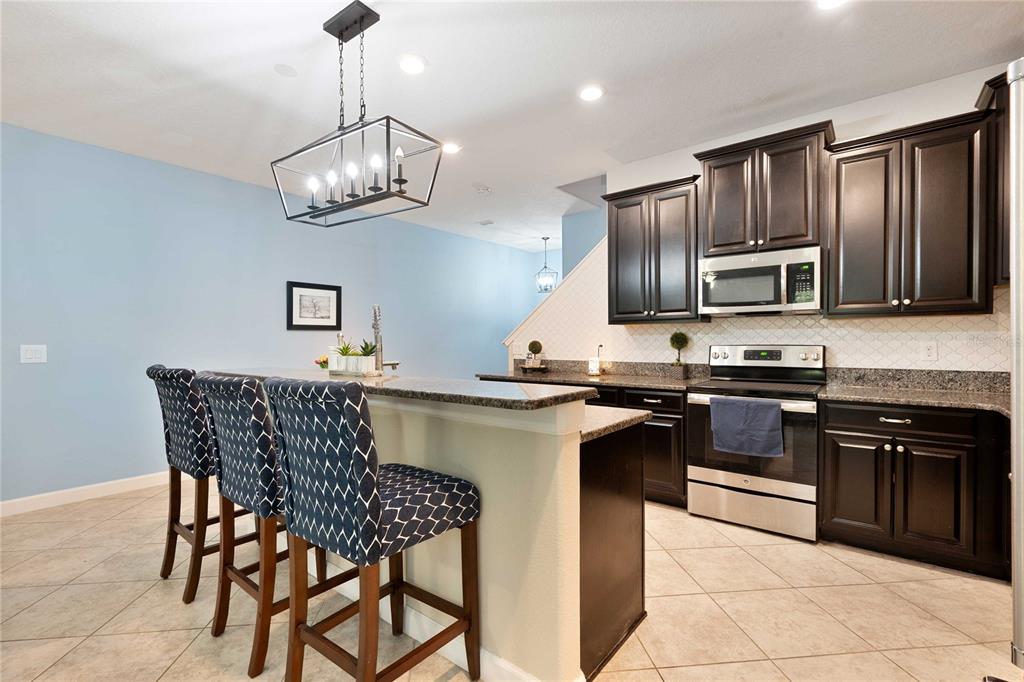 17365 Old Tobacco Road Lutz, FL 33558 - Photo 9 of 44 a kitchen with stainless steel appliances granite countertop a stove a sink dishwasher a dining table and chairs with wooden floor