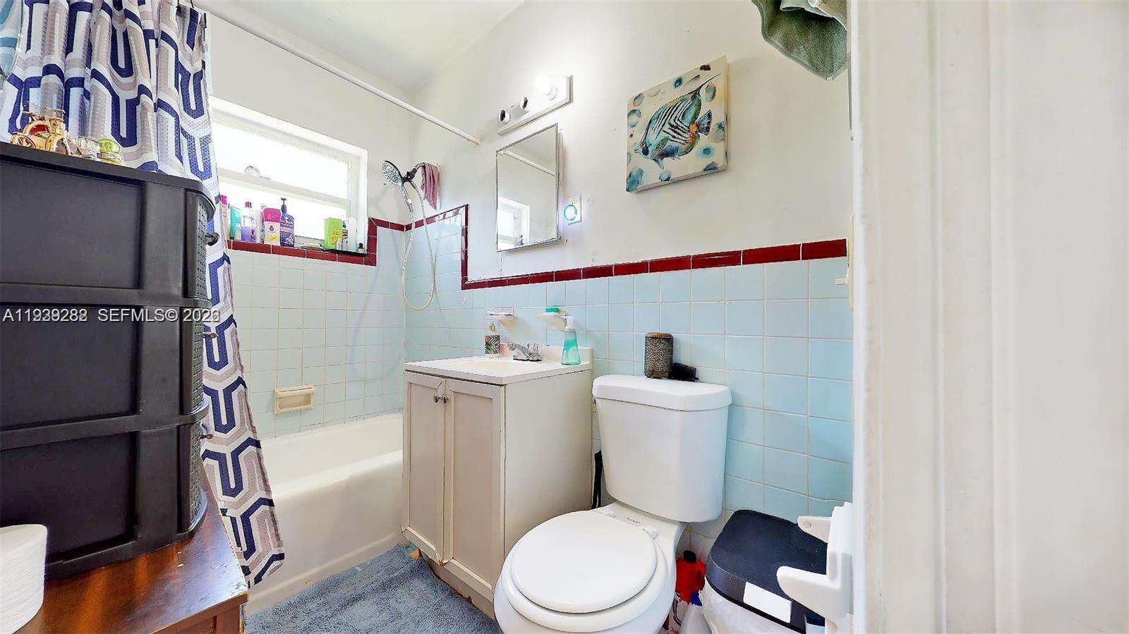 2499 Southwest 27th Street, Unit 1 Miami, FL 33133 - Photo 13 of 14 a white toilet sitting next to a bathroom sink and a mirror