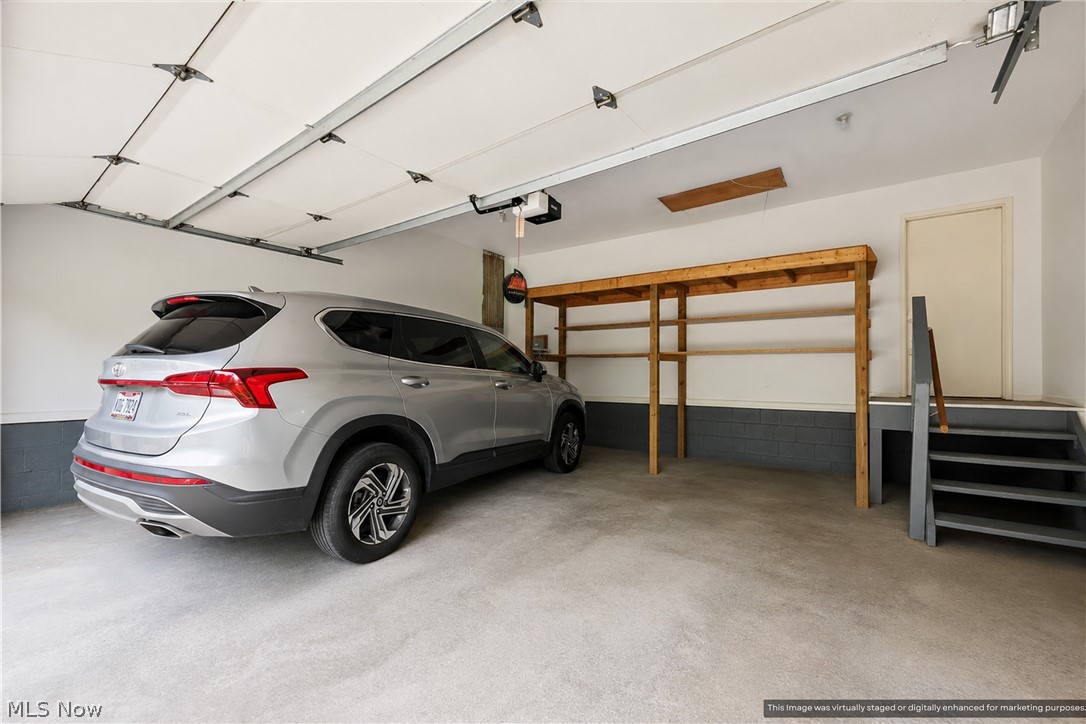 1835 Lynn Road Kent, OH 44240 - Photo 40 of 48 Attached two-car garage featuring a concrete floor, built-in wooden shelving, and a separate service door
