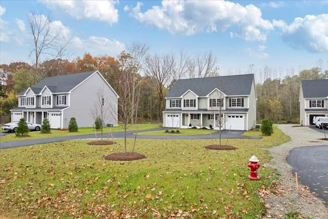 a view of a white house with a large windows and a yard with plants and trees in the background