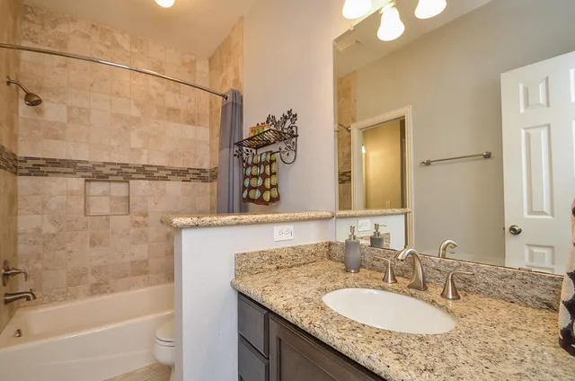 a bathroom with a granite countertop sink a mirror and a bathtub