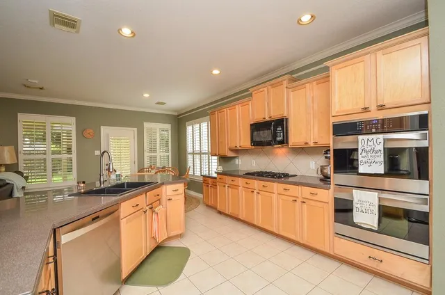 a large kitchen with stainless steel appliances granite countertop a stove top oven a sink dishwasher a dining table and chairs with wooden floor