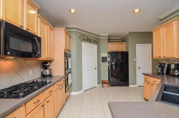 a large kitchen with stainless steel appliances granite countertop a stove top oven a sink dishwasher a dining table and chairs with wooden floor
