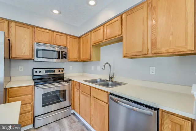 a kitchen with stainless steel appliances granite countertop a sink a stove a microwave and wooden cabinets