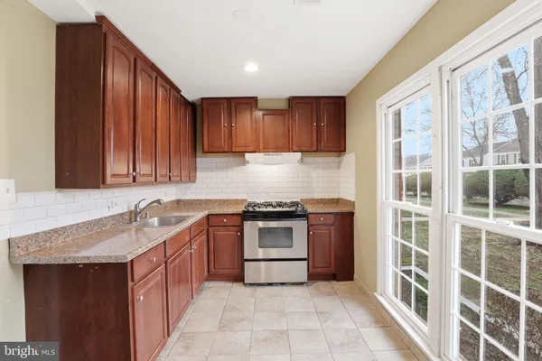 a kitchen with kitchen island granite countertop a sink stove and cabinets
