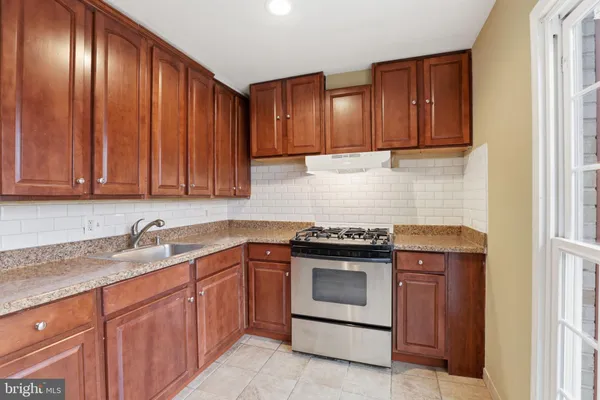 a kitchen with granite countertop stainless steel appliances wooden cabinets and a sink