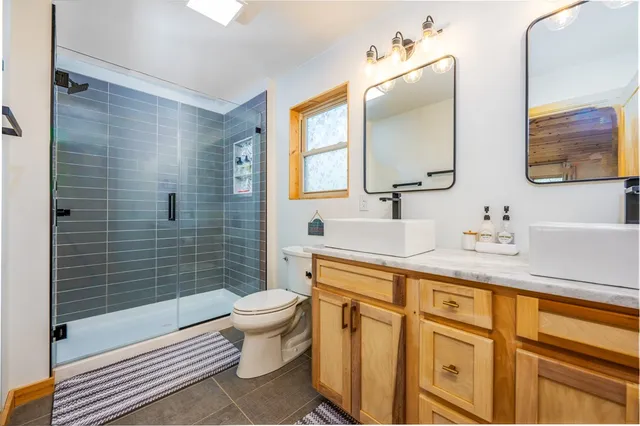 a bathroom with a sink a toilet a mirror and shower