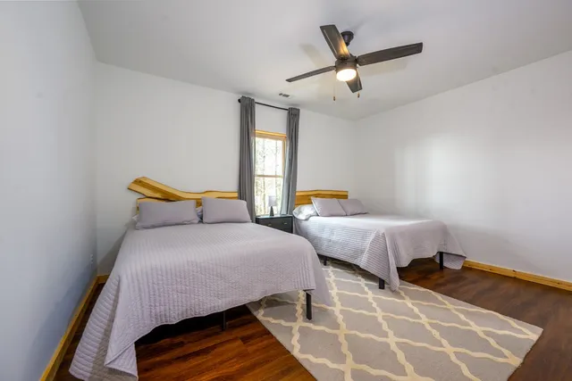a bedroom with two beds and ceiling fan