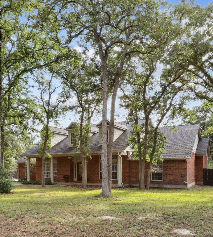 View of front of house featuring a shingled roof, brick siding, and a front yard