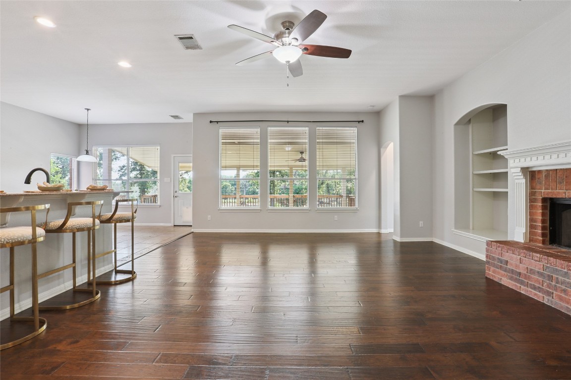 120 Juniper Trail Elgin, TX 78621 - Photo 11 of 32 Unfurnished living room with recessed lighting, dark wood-style floors, a ceiling fan, a brick fireplace, and built in features