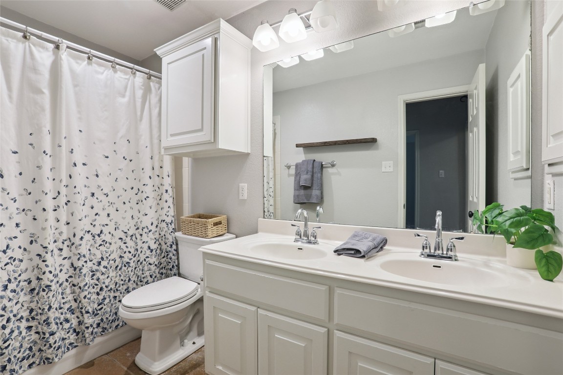120 Juniper Trail Elgin, TX 78621 - Photo 19 of 32 Bathroom with double vanity, a shower with shower curtain, and dark tile patterned floors