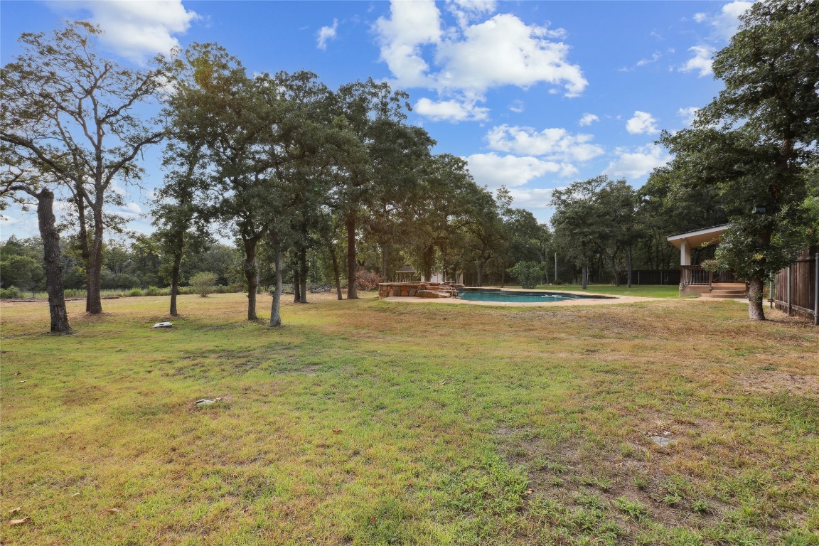120 Juniper Trail Elgin, TX 78621 - Photo 29 of 32 View of green lawn with an outdoor pool and a patio