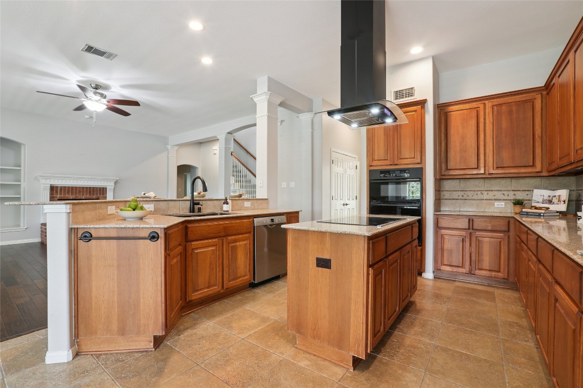120 Juniper Trail Elgin, TX 78621 - Photo 8 of 32 Kitchen with a center island, tasteful backsplash, brown cabinets, light stone counters, and island exhaust hood