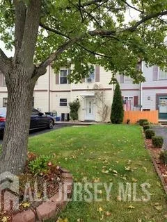 a white house in front of a big yard with large trees