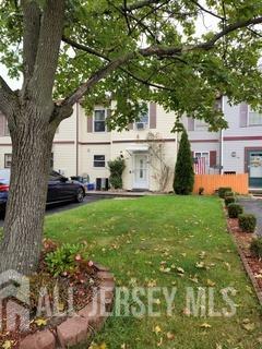 a white house in front of a big yard with large trees