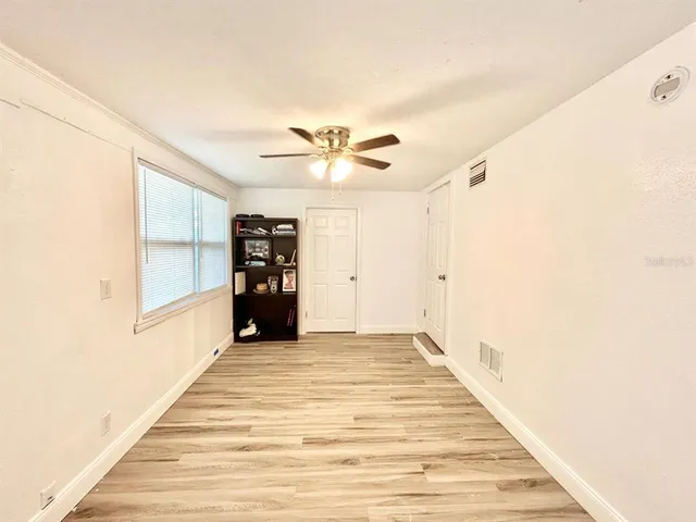 a view of an empty room with window and a ceiling fan
