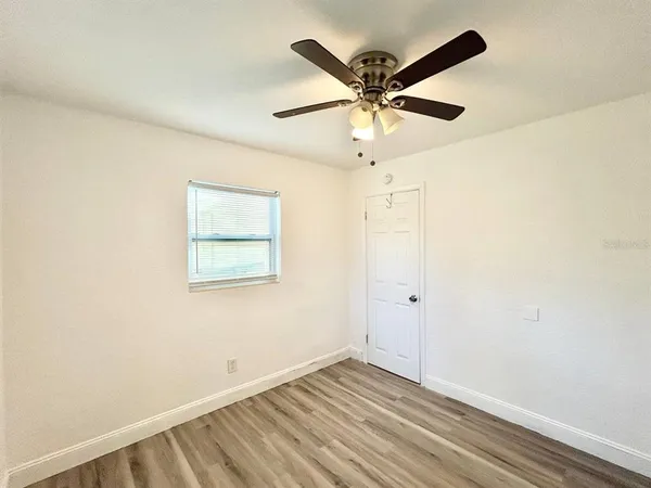 an empty room with a window and a fan