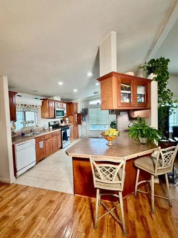 a kitchen with stainless steel appliances kitchen island granite countertop a table chairs and a refrigerator