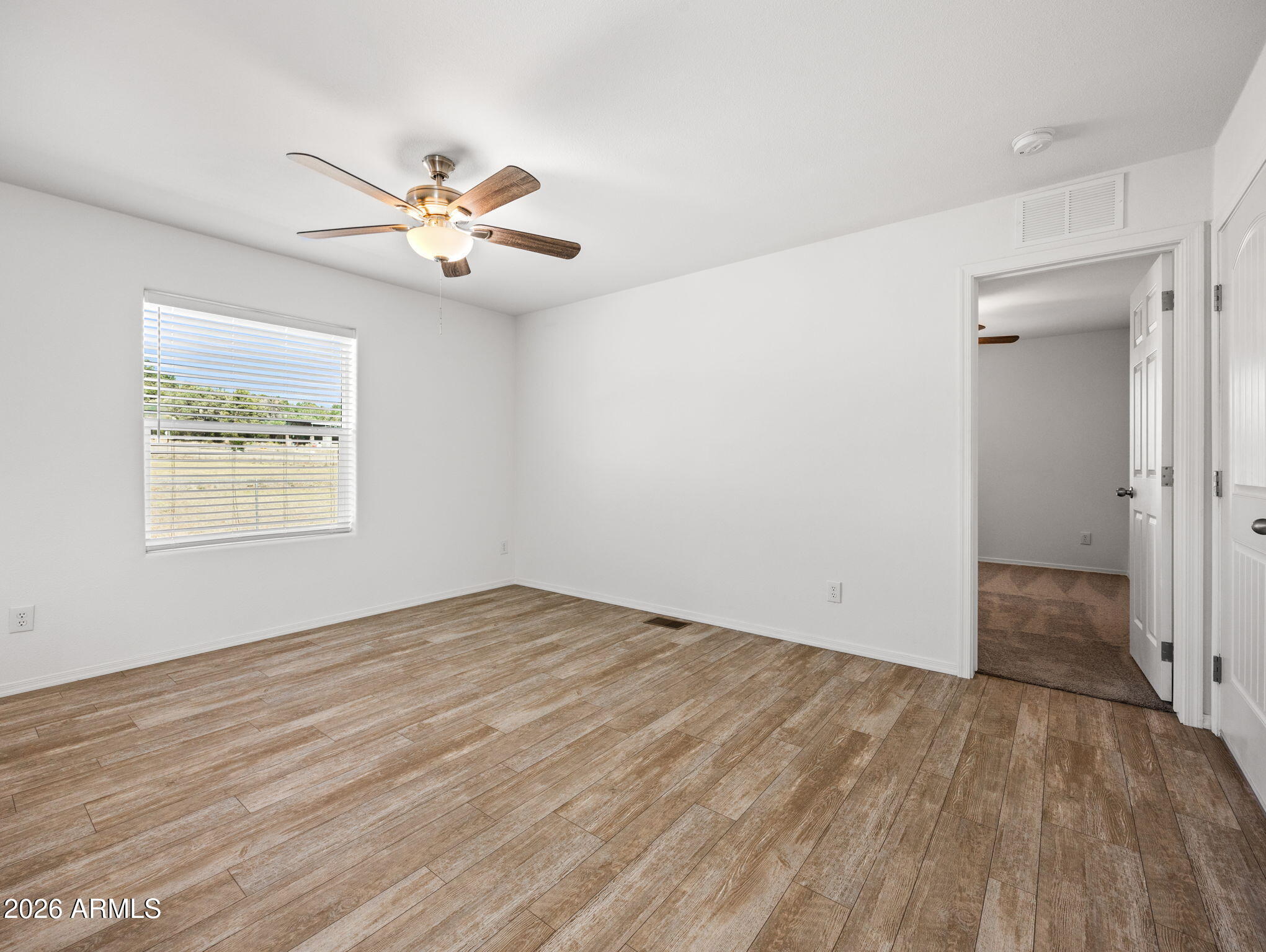 18296 Frontier Road Peeples Valley, AZ 86332 - Photo 15 of 44 an empty room with wooden floor fan and windows
