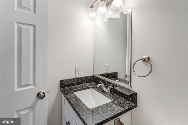 a bathroom with a granite countertop sink a light fixture and a mirror