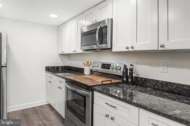 a kitchen with stainless steel appliances granite countertop a sink a stove and a microwave