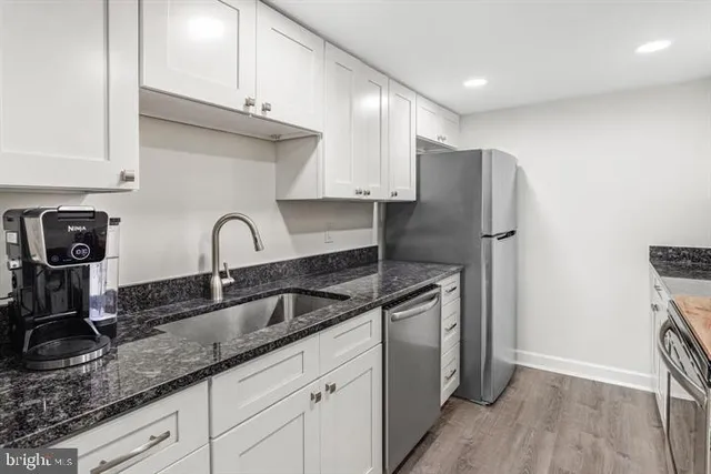 a kitchen with stainless steel appliances granite countertop a sink a refrigerator and wooden cabinets