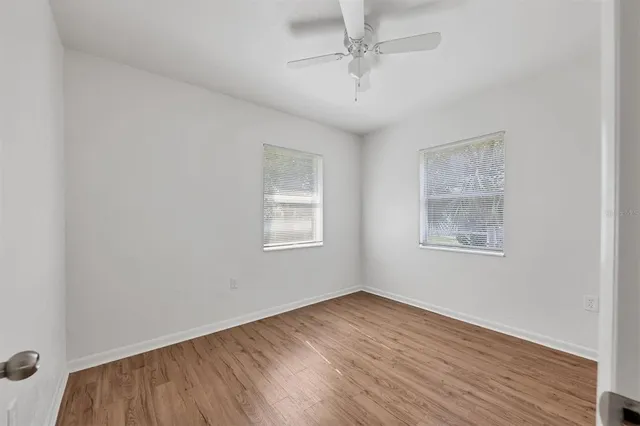 a view of empty room with wooden floor and fan