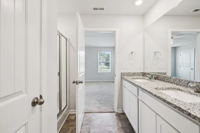 a bathroom with a granite countertop sink a mirror and a shower
