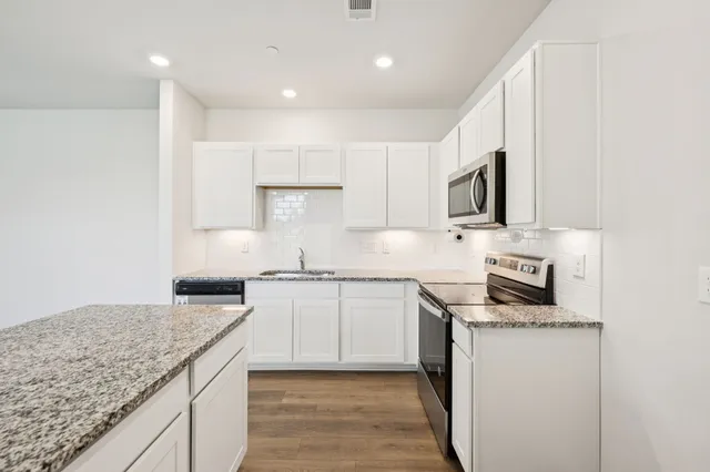 a kitchen with granite countertop white cabinets and white appliances