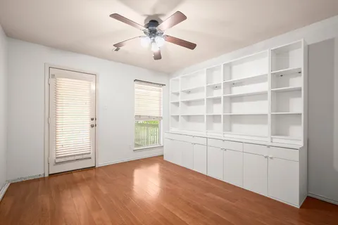 a view of an empty room with a window and wooden floor