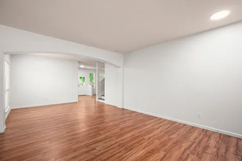 a view of empty room with wooden floor and window