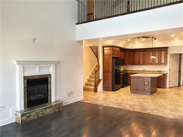 a view of an empty room with wooden floor and a fireplace