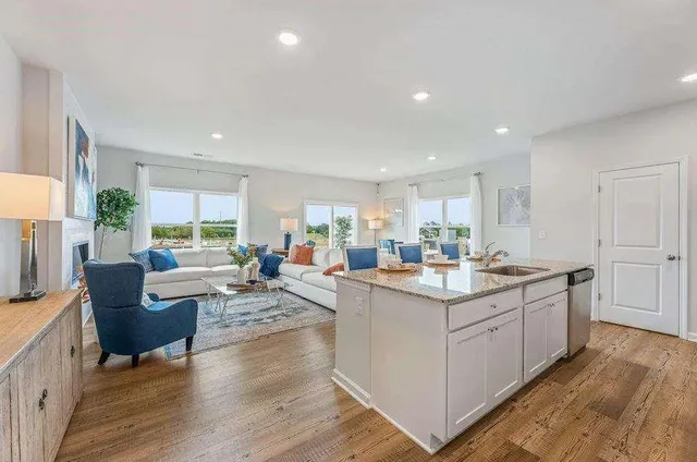 a view of kitchen with kitchen island stainless steel appliances living room living room and wooden floor