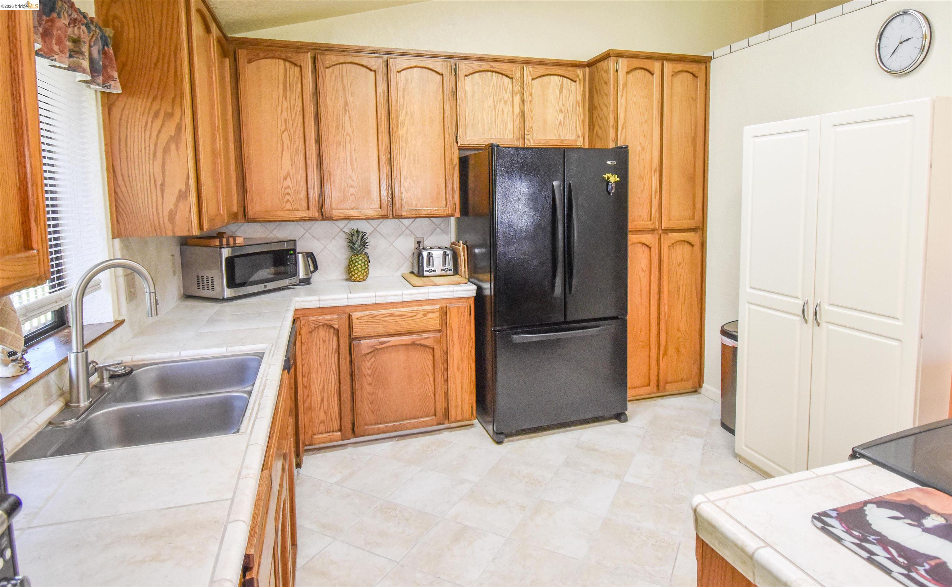15170 Potato Ranch Road Sonora, CA 95370 - Photo 18 of 49 Kitchen with tile countertops, freestanding refrigerator, wood finish cabinetry, stainless steel microwave, and lofted ceiling