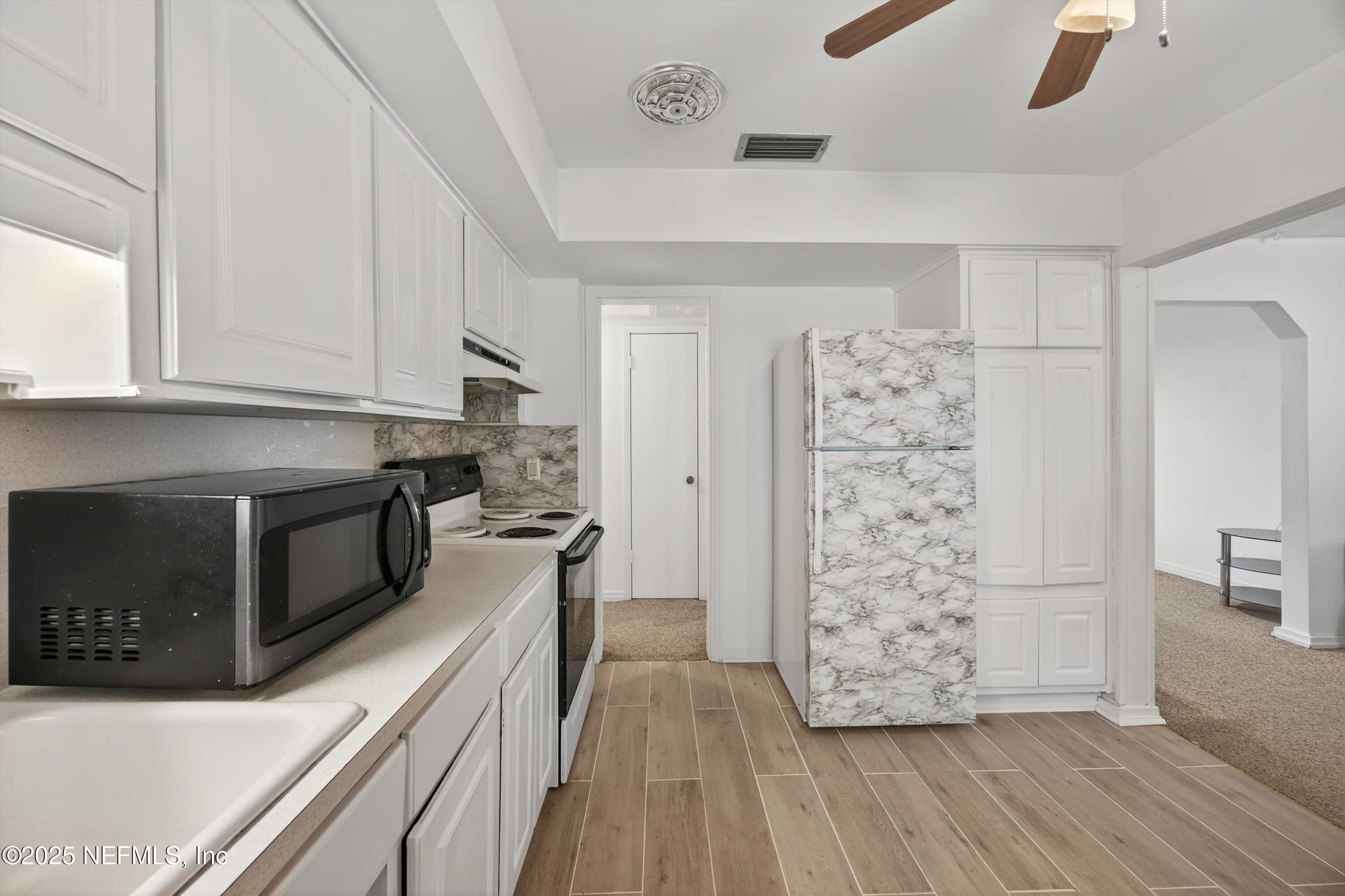 2630 Bywood Road Jacksonville, FL 32211 - Photo 11 of 35 a kitchen with granite countertop a refrigerator a stove and white cabinets with wooden floor