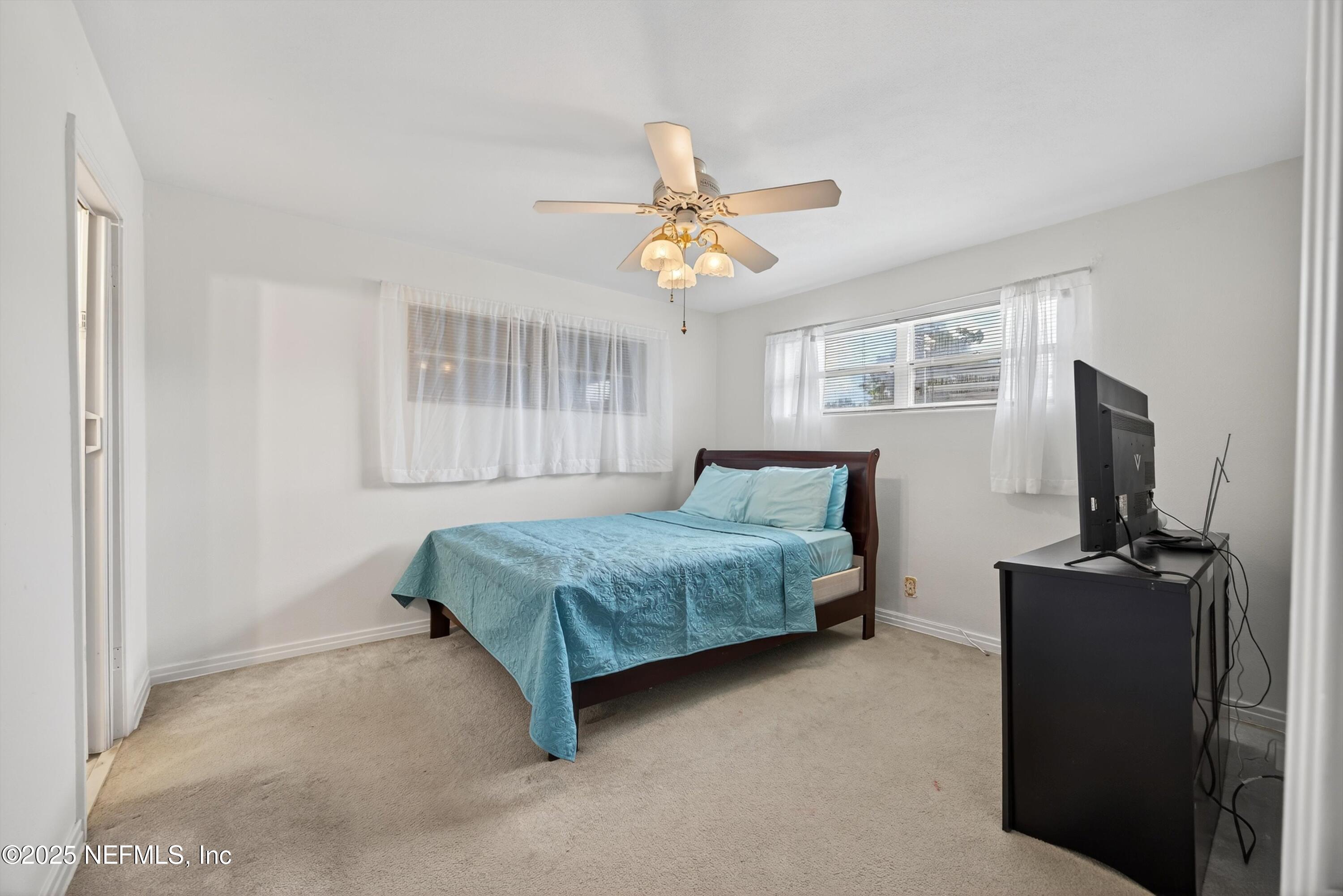 2630 Bywood Road Jacksonville, FL 32211 - Photo 24 of 35 a bedroom with a bed a chandelier and a flat tv