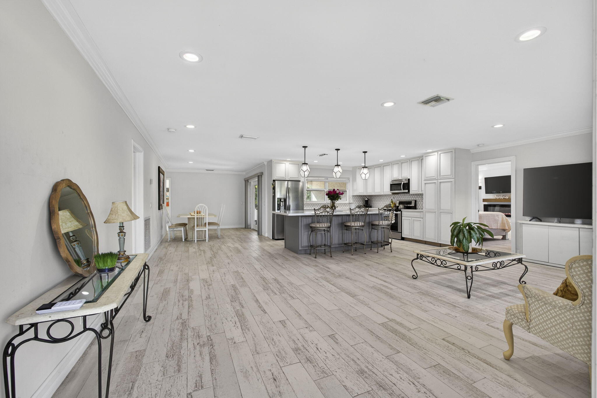 16490 Rustic Road Wellington, FL 33470 - Photo 3 of 81 a living room with furniture a flat screen tv and kitchen view