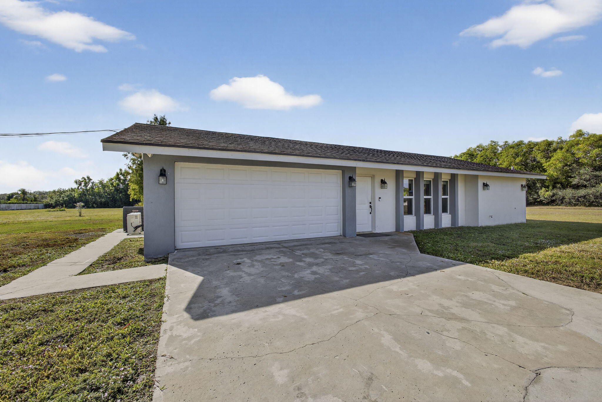 16490 Rustic Road Wellington, FL 33470 - Photo 40 of 81 a view of a house with a yard and a garage
