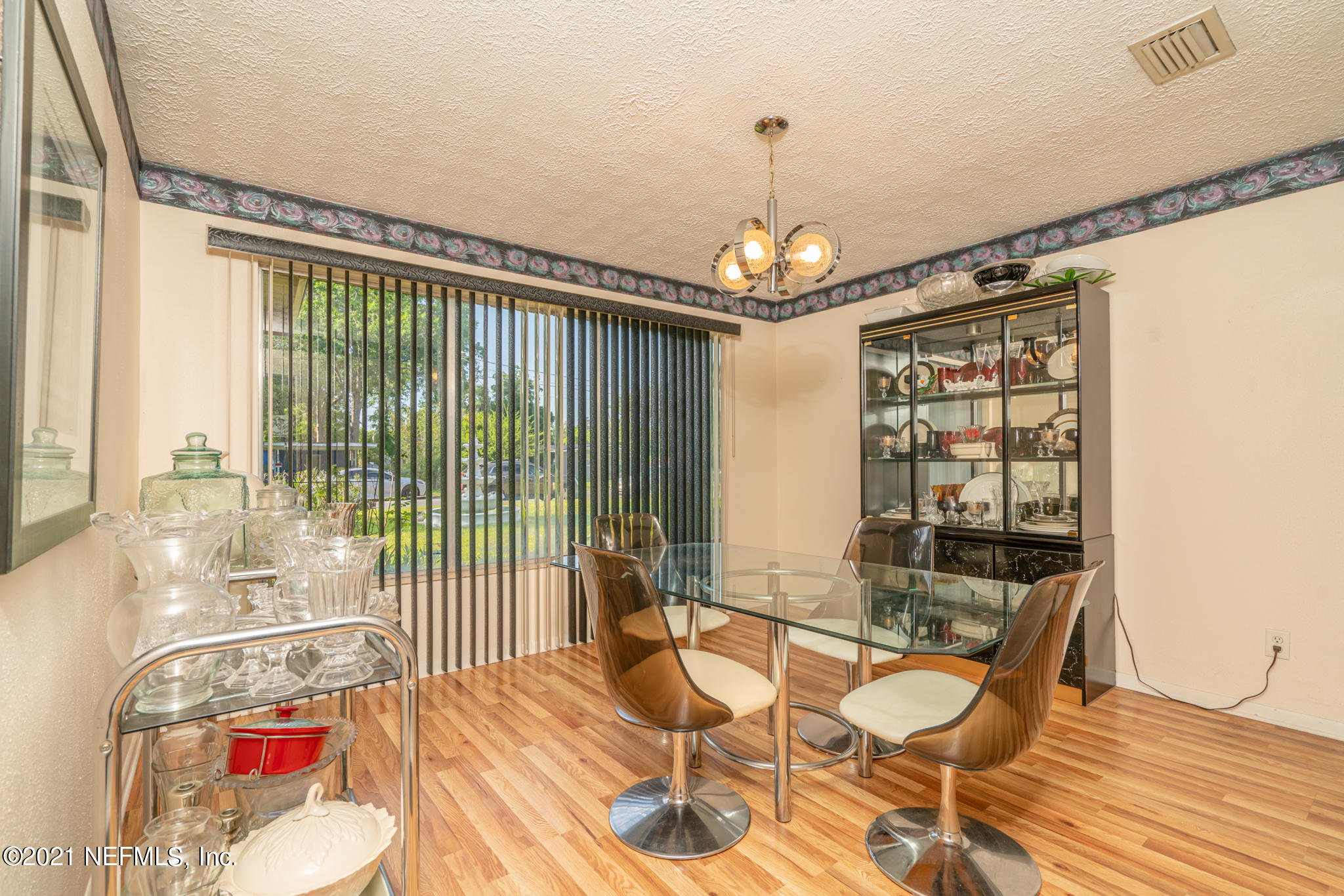 4612 Castleton Drive Jacksonville, FL 32208 - Photo 21 of 41 a dining room with wooden floor a chandelier a glass table and chairs
