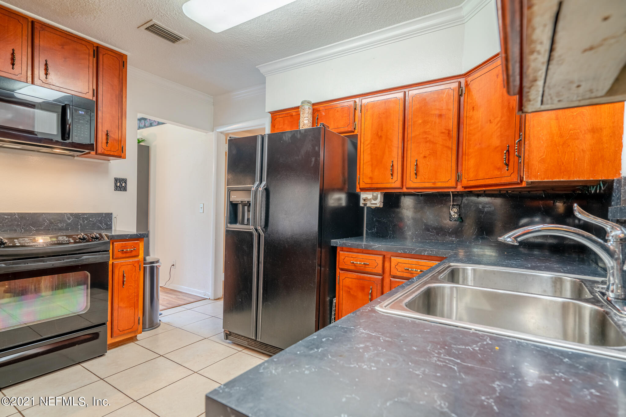 4612 Castleton Drive Jacksonville, FL 32208 - Photo 22 of 41 a kitchen with stainless steel appliances a sink a stove and a microwave with wooden floor
