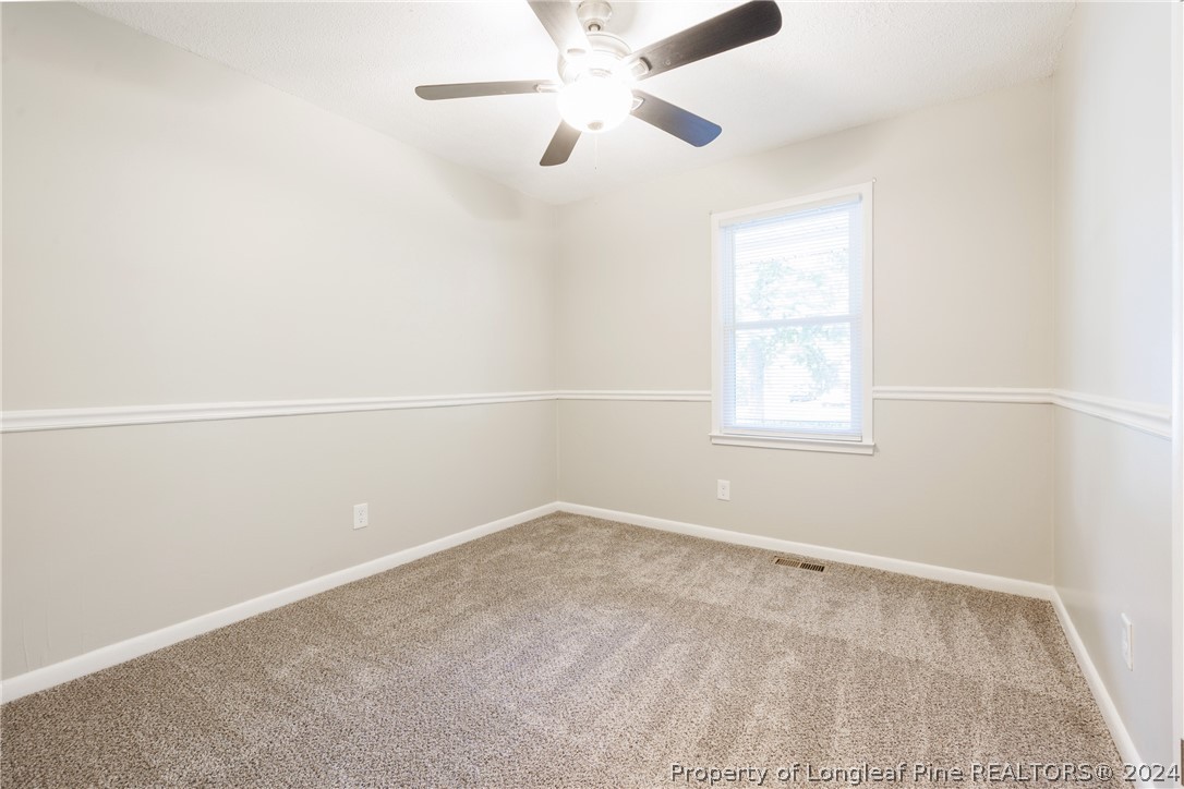 5851 Columbine Road Fayetteville, NC 28306 - Photo 14 of 25 an empty room with a window and a ceiling fan