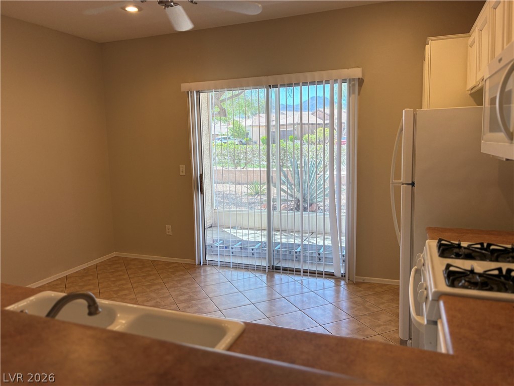 2523 Romanza Road Henderson, NV 89052 - Photo 9 of 24 A well-lit kitchen with tiled flooring and a convenient sliding glass door to the outside.