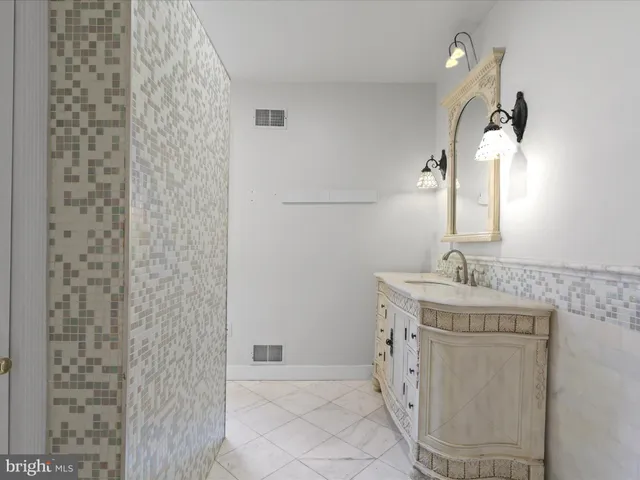 a bathroom with a granite countertop sink a mirror and shower