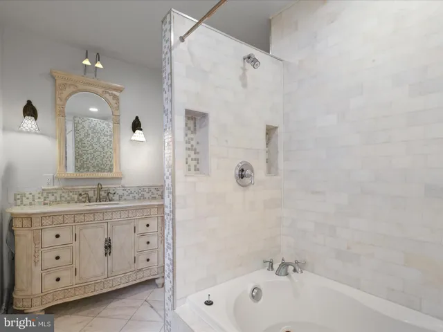 a bathroom with a granite countertop sink a mirror a bathtub and shower