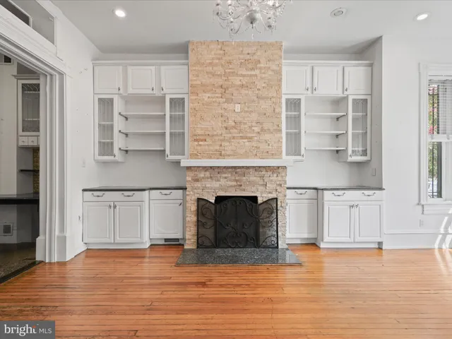a living room with stainless steel appliances wooden floor and a fireplace