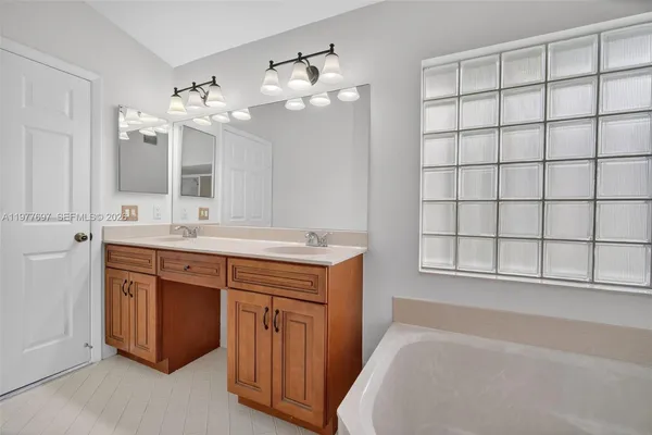 a spacious bathroom with a double vanity sink large mirror and a bathtub