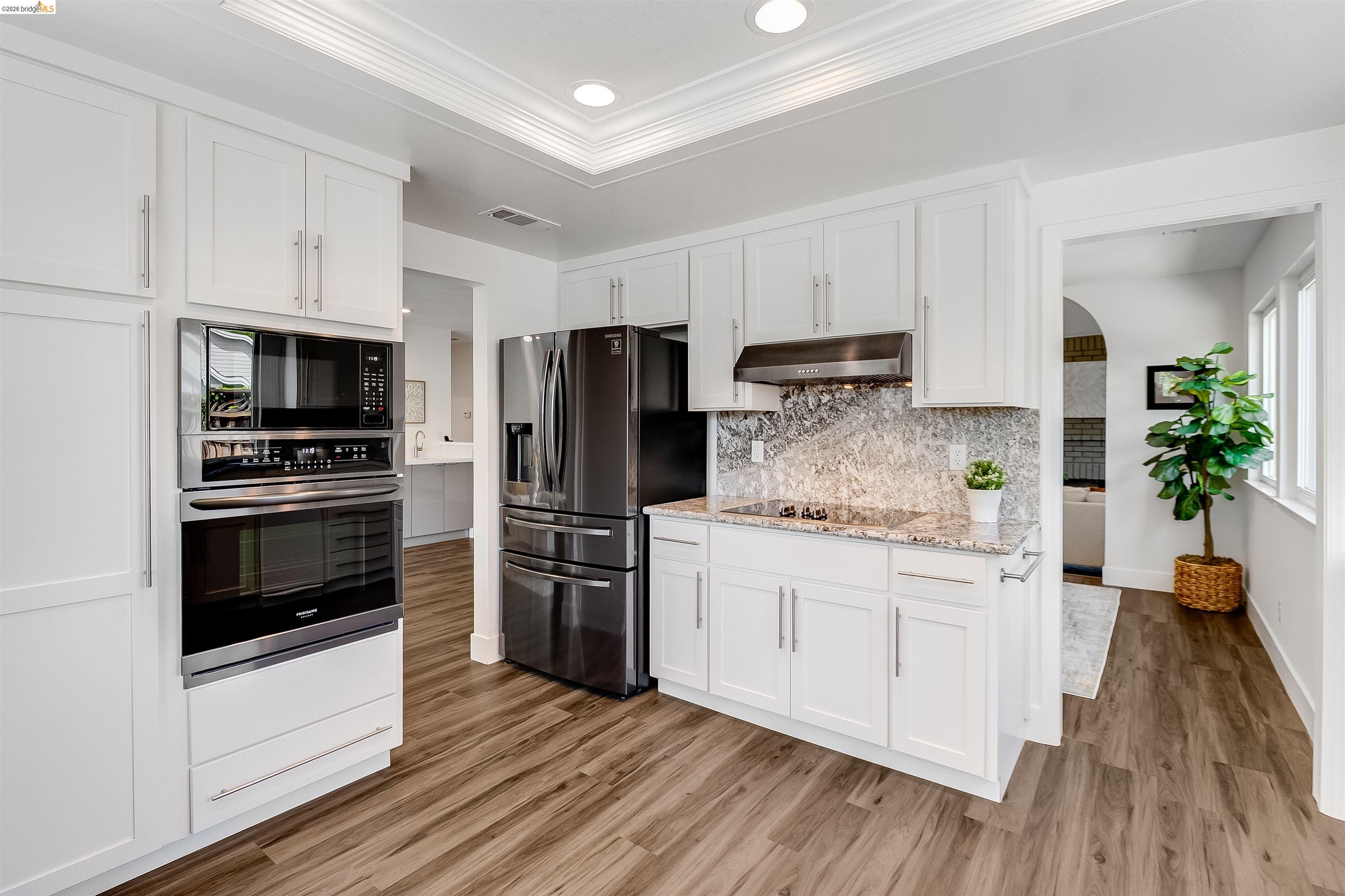 9980 Mangos Drive San Ramon, CA 94583 - Photo 15 of 41 Kitchen featuring white cabinets, black appliances, arched walkways, crown molding, and light wood-type flooring